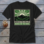 A black t-shirt featuring a green and cream graphic of mountains and sunburst rays with text.