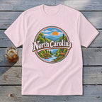 Pink t-shirt with a circular graphic of North Carolina mountains, river, and a deer.