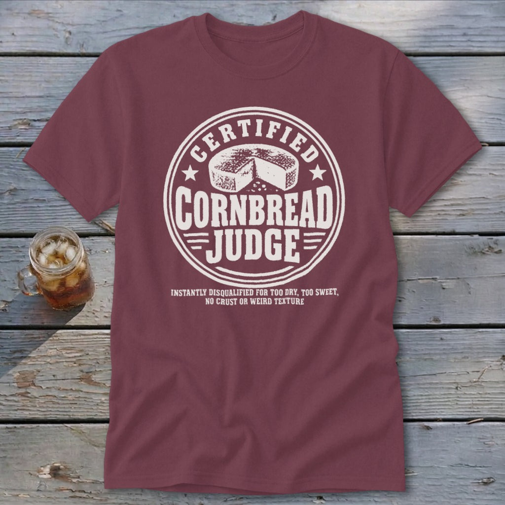 A maroon crewneck t-shirt featuring a white distressed graphic that reads Certified Cornbread Judge.