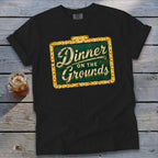 A black t-shirt features a vintage marquee sign graphic that reads Dinner on the Grounds.