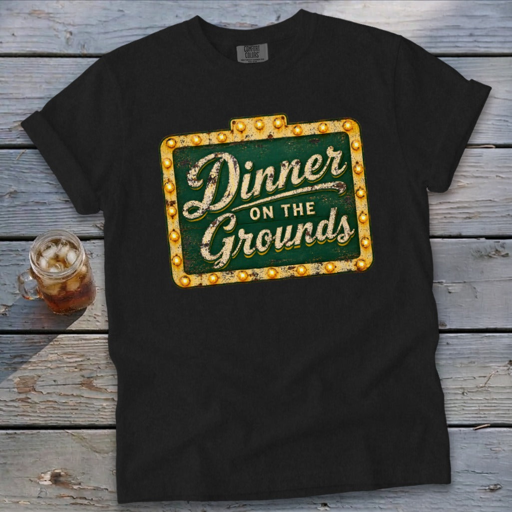 A black t-shirt features a vintage marquee sign graphic that reads Dinner on the Grounds.