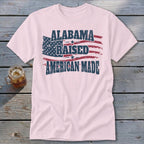Pink t-shirt with distressed American flag graphic and text "Alabama Raised American Made".