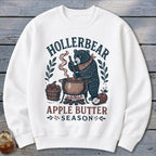 White sweatshirt with "Hollerbear Apple Butter Season" graphic of a bear stirring a pot.