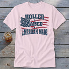 Pink t-shirt with distressed American flag graphic and text "HOLLER RAISED AMERICAN MADE".
