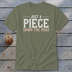 Olive green t-shirt with "JUST A PIECE DOWN THE ROAD" text.
