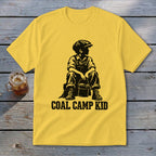 Yellow t-shirt with black graphic of a boy in overalls and cap holding a bucket, "COAL CAMP KID" text.