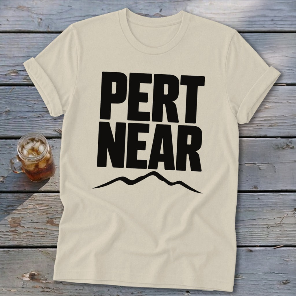 Light cream t-shirt featuring bold black text reading Pert Near above a mountain range graphic.