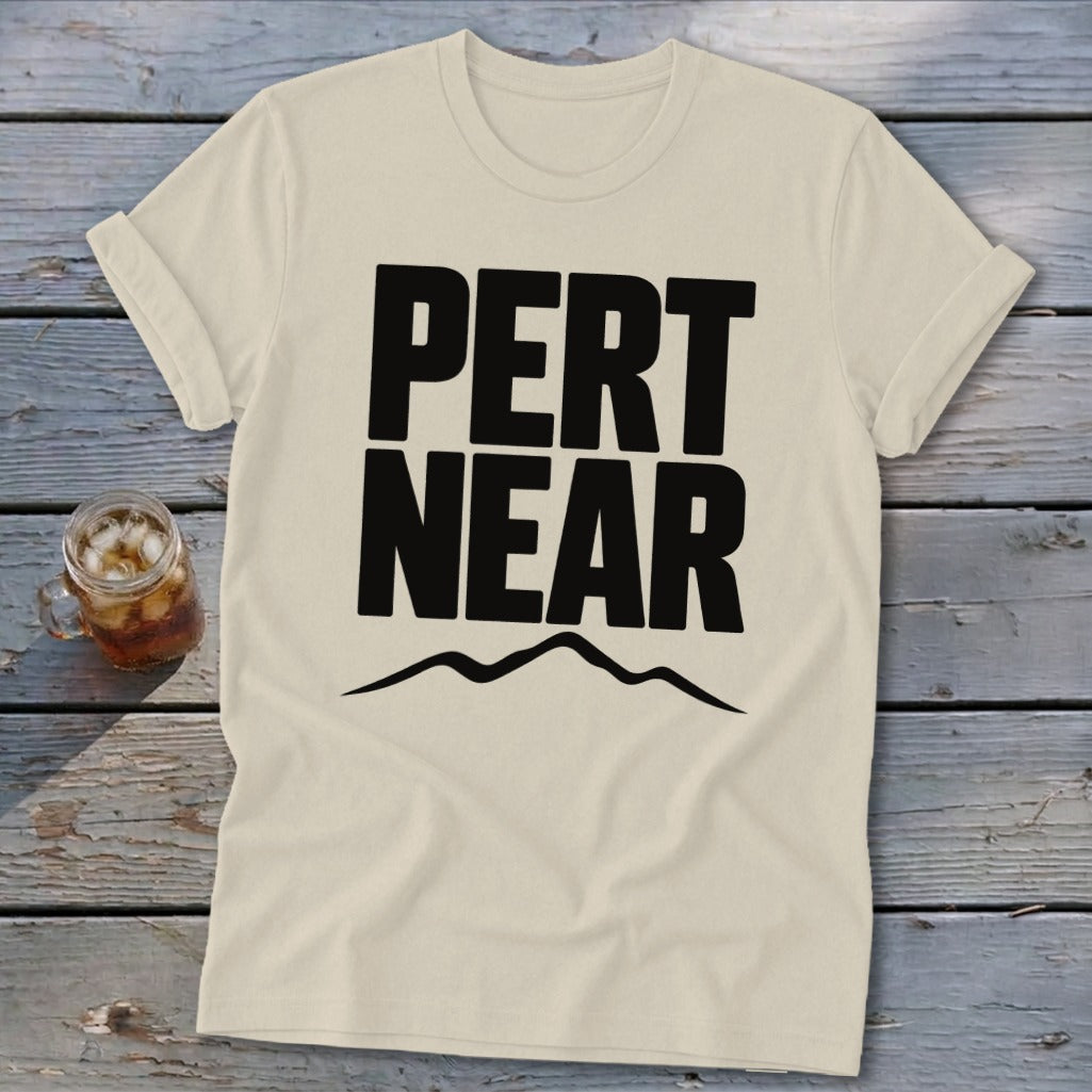 Light cream t-shirt featuring bold black text reading Pert Near above a mountain range graphic.