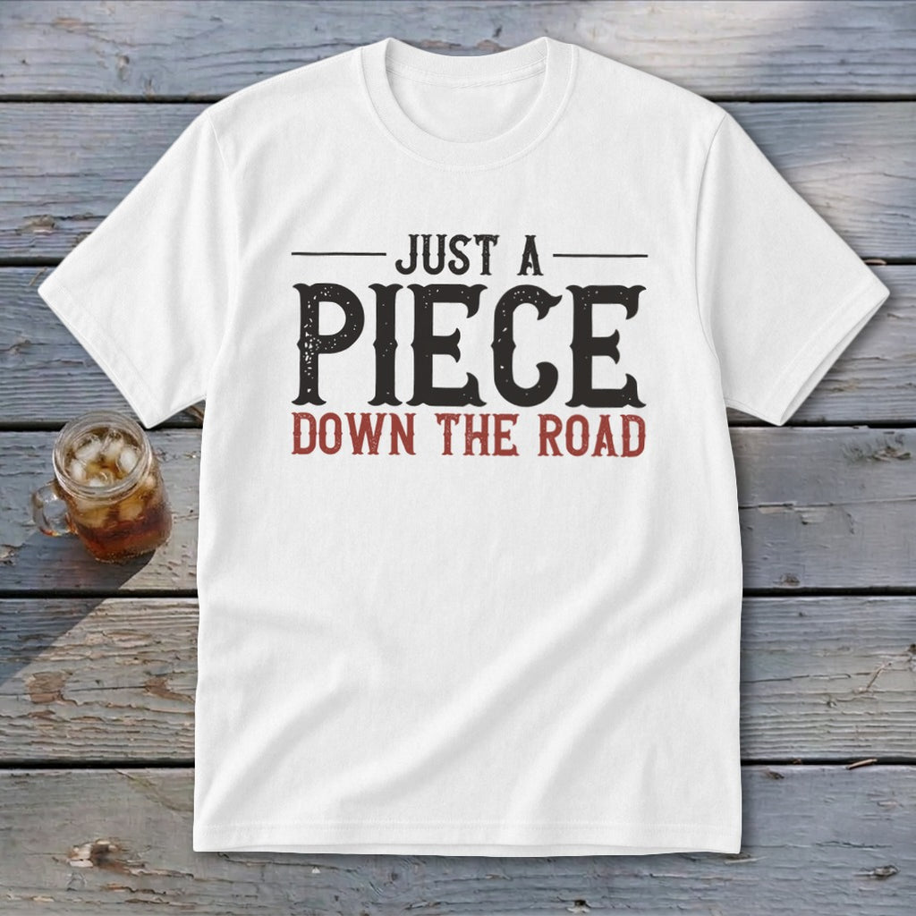 White t-shirt with "JUST A PIECE DOWN THE ROAD" text in black and red.