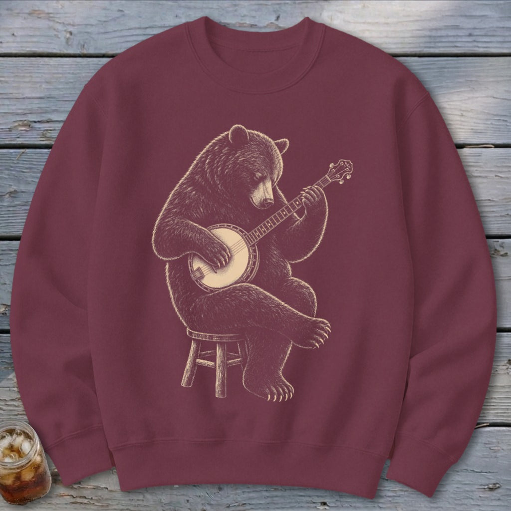 Bear playing banjo seated on a stool, printed on a maroon sweatshirt.