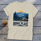 T-shirt with a graphic depicting a house in a mountain landscape and the text "THE HOME PLACE".
