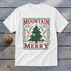 A white short-sleeved t-shirt featuring a vintage Christmas tree graphic with the text Mountain Merry.