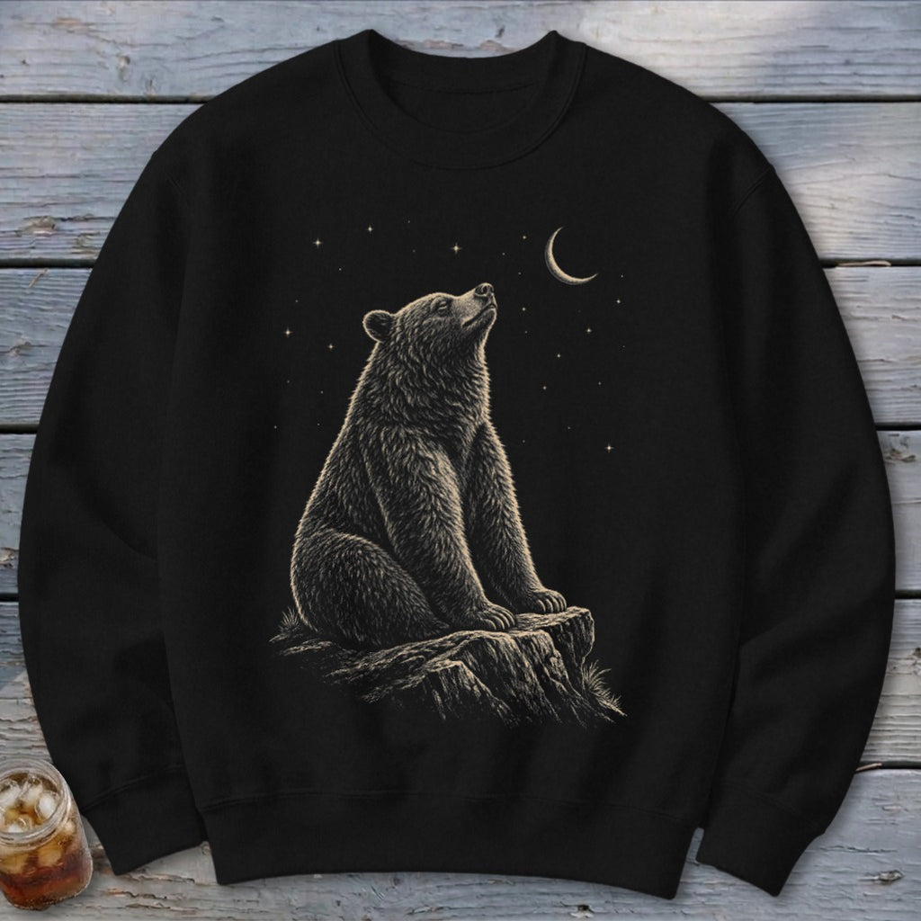 Black crewneck sweatshirt with a bear sitting on a rock under a crescent moon and stars.