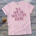 Pink t-shirt with dark pink text reading "WE SPEAK MOUNTAIN HERE"