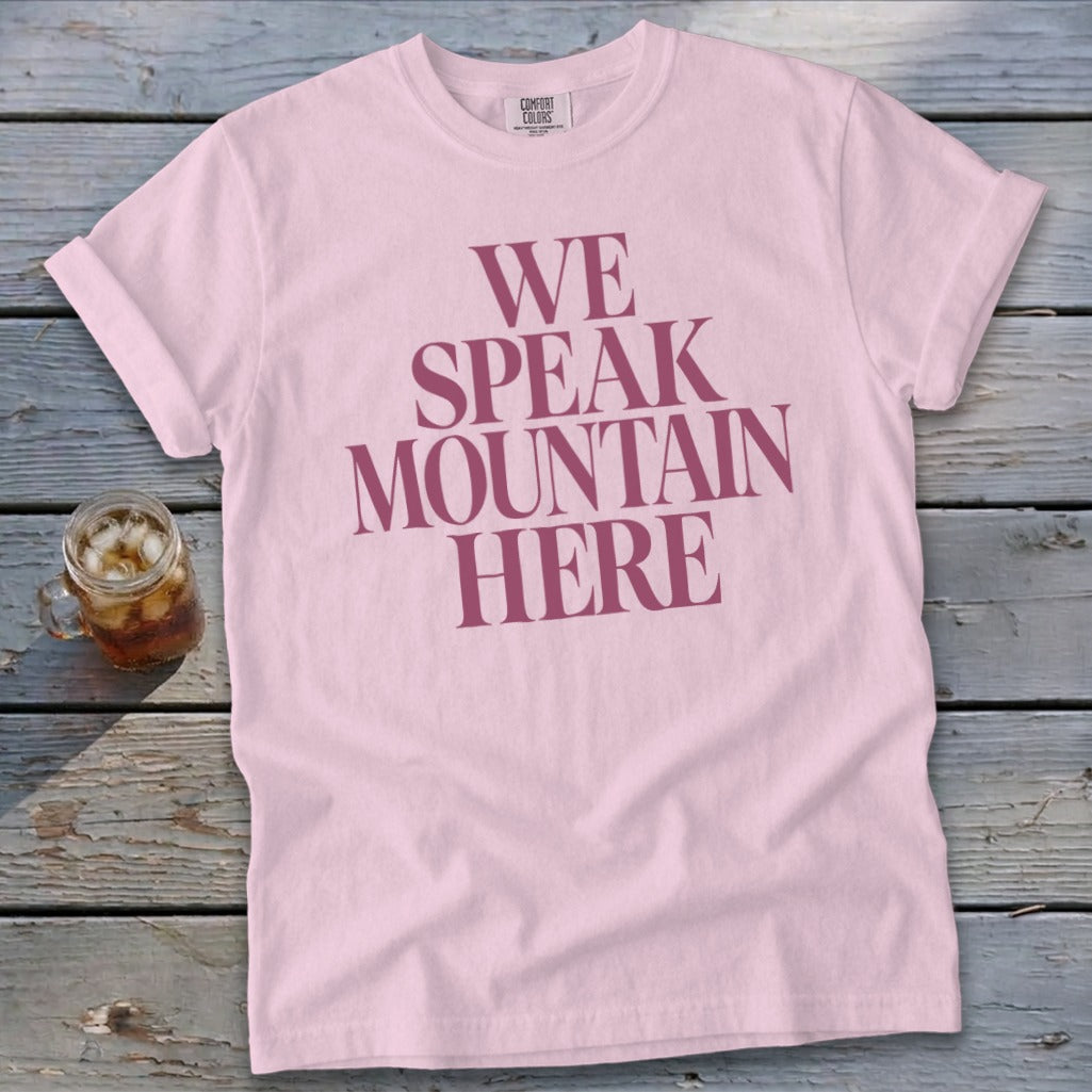 Pink t-shirt with dark pink text reading "WE SPEAK MOUNTAIN HERE"