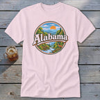 Pink t-shirt with circular Alabama graphic featuring mountains, river, deer, and sunset.