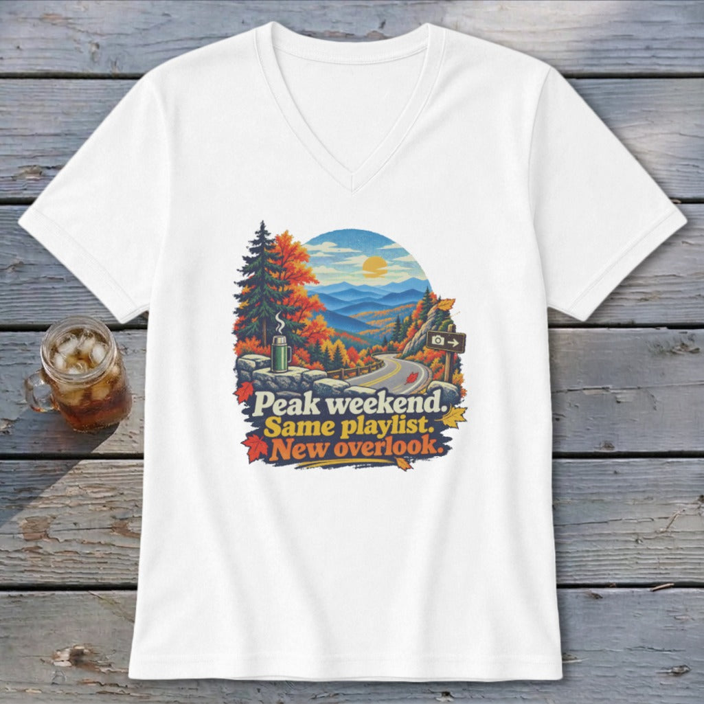 White v-neck t-shirt with mountain overlook graphic and text "Peak weekend. Same playlist. New overlook."