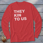Red long sleeve shirt with white text "THEY KIN TO US".