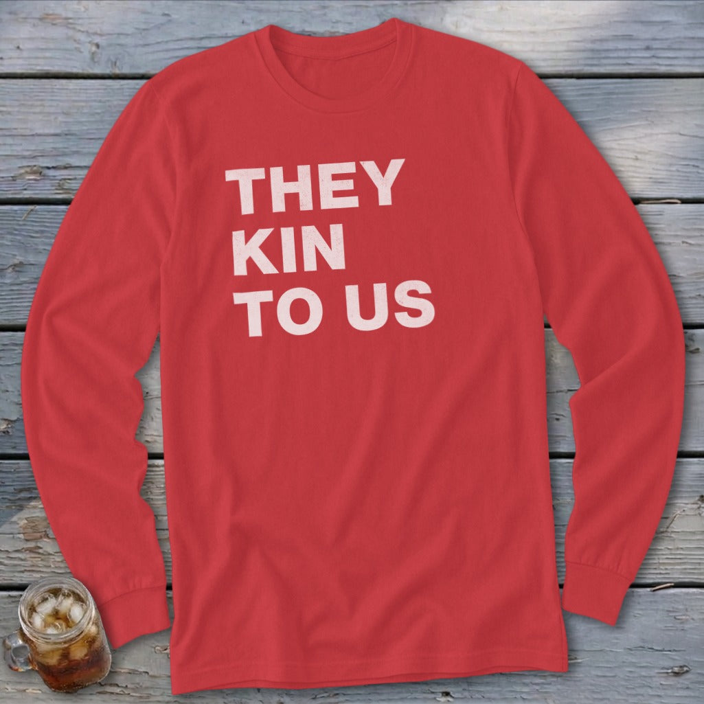 Red long sleeve shirt with white text "THEY KIN TO US".