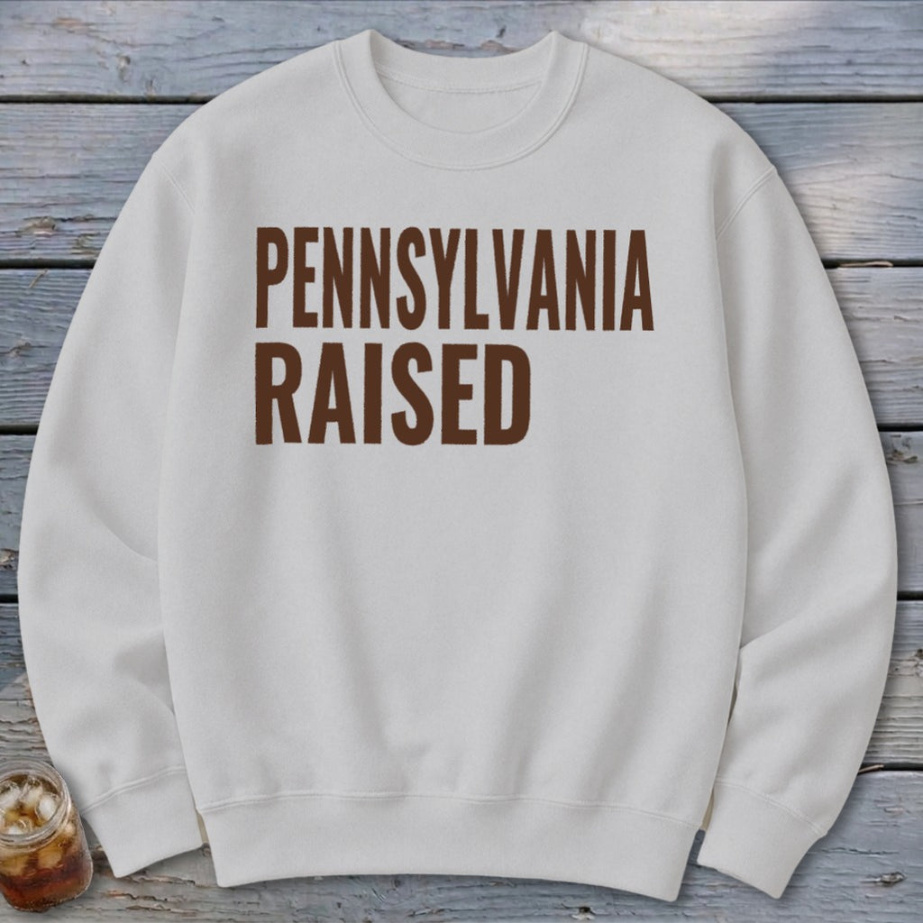 White sweatshirt with brown text reading "PENNSYLVANIA RAISED".