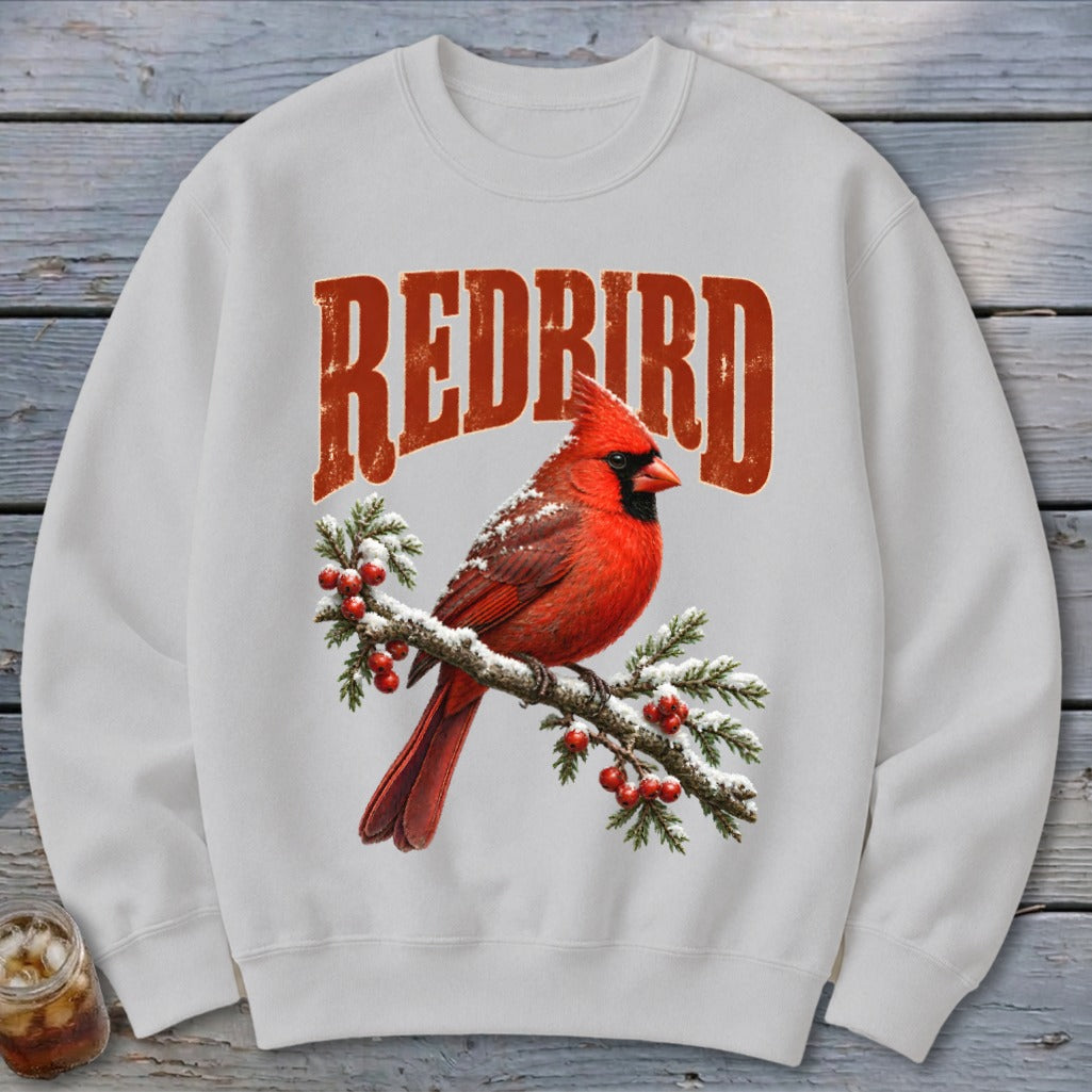Light gray crewneck sweatshirt featuring a graphic of a red cardinal on a snowy branch with "REDBIRD" text.