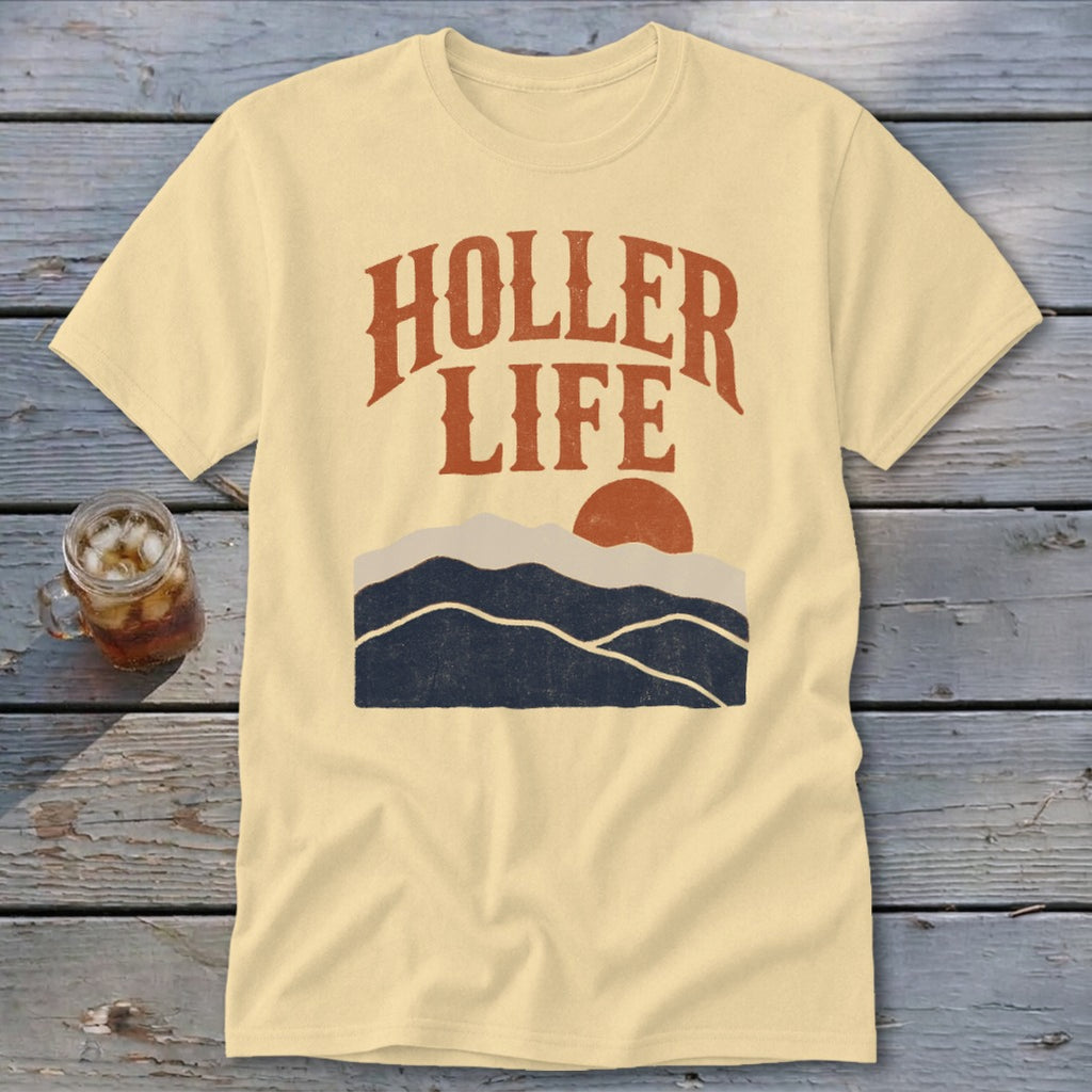 A cream-colored t-shirt with brown text reading "HOLLER LIFE" above a mountain and sun graphic.
