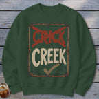 Green sweatshirt with a distressed sign graphic that reads "CRICK" crossed out and "CREEK" with a checkmark.