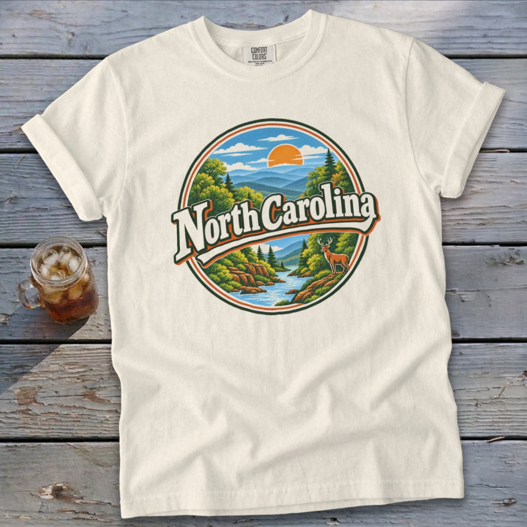 Cream t-shirt with a circular graphic of mountains, river, trees, deer, and "North Carolina".