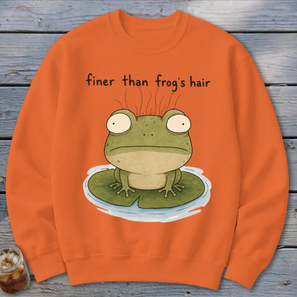 An orange sweatshirt features an illustration of a green frog on a lily pad with text reading finer than frog's hair.