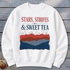 White crewneck sweatshirt featuring red and blue patriotic text and layered mountain graphics.
