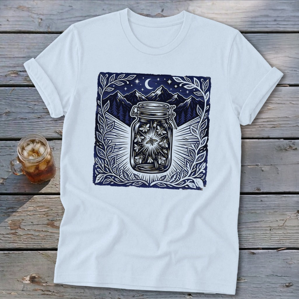 White t-shirt with a dark blue graphic of fireflies in a jar against mountains and moon.
