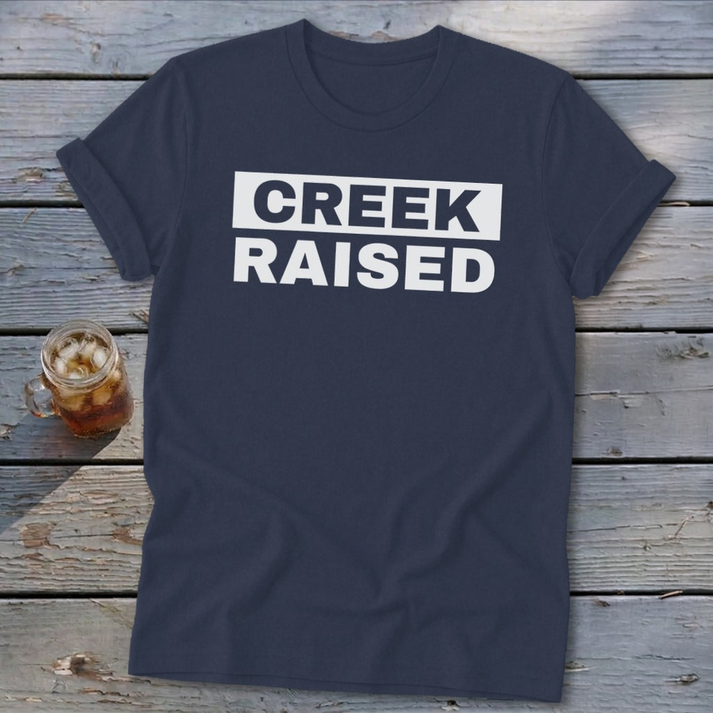 Navy t-shirt with white text that reads "CREEK RAISED" inside a white rectangle.