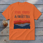 An orange short-sleeved t-shirt featuring the text STARS, STRIPES, AND SWEET TEA above mountain graphics.