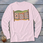 Light pink long-sleeve t-shirt with a vintage graphic of three quilts hanging on a clothesline against rolling hills.