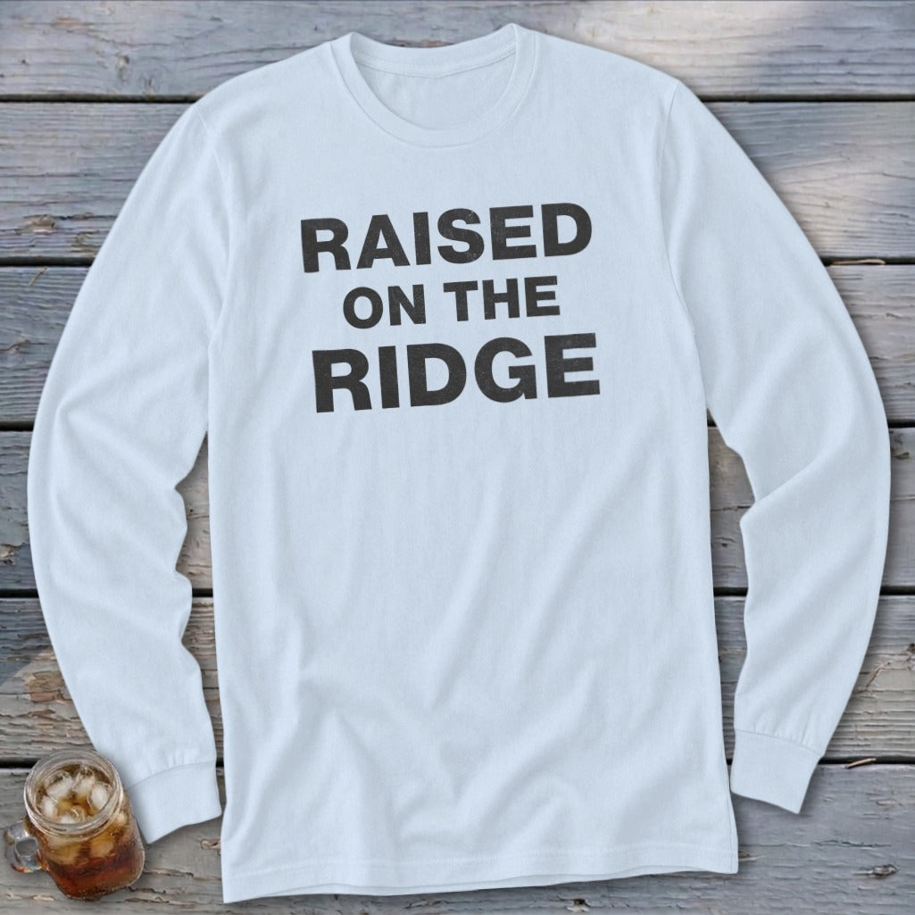 White long-sleeved t-shirt with black text "RAISED ON THE RIDGE."