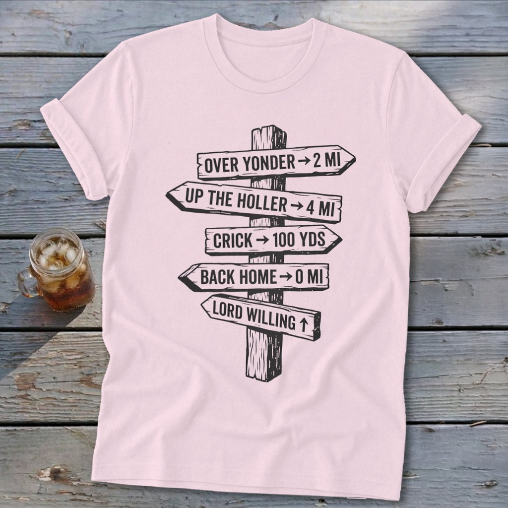 Light pink short-sleeved t-shirt with a black graphic of directional wooden signs on a rustic wooden background.