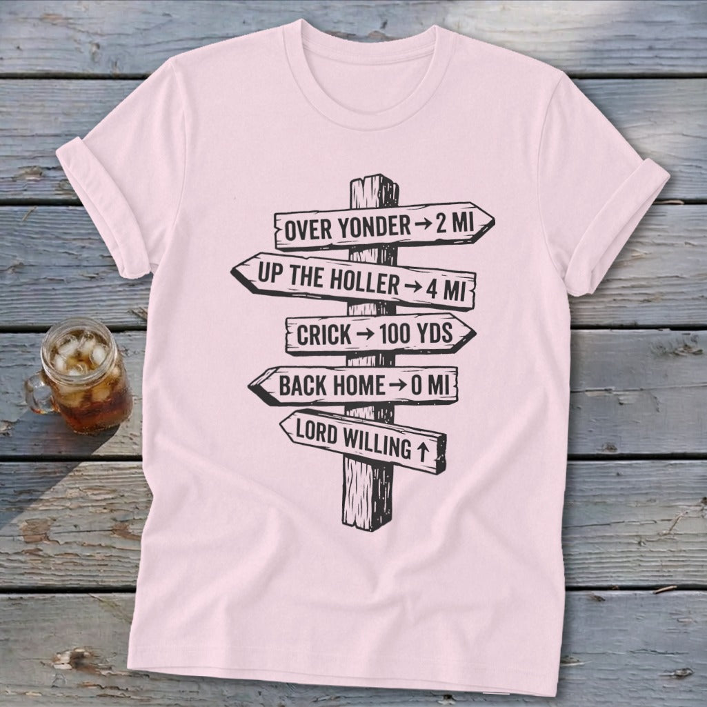 Light pink short-sleeved t-shirt with a black graphic of directional wooden signs on a rustic wooden background.