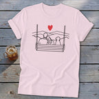Couple and dog on swing under a heart, with mountain background.