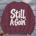 A maroon crewneck sweatshirt with the white text "Still A-Goin'" printed on the front.