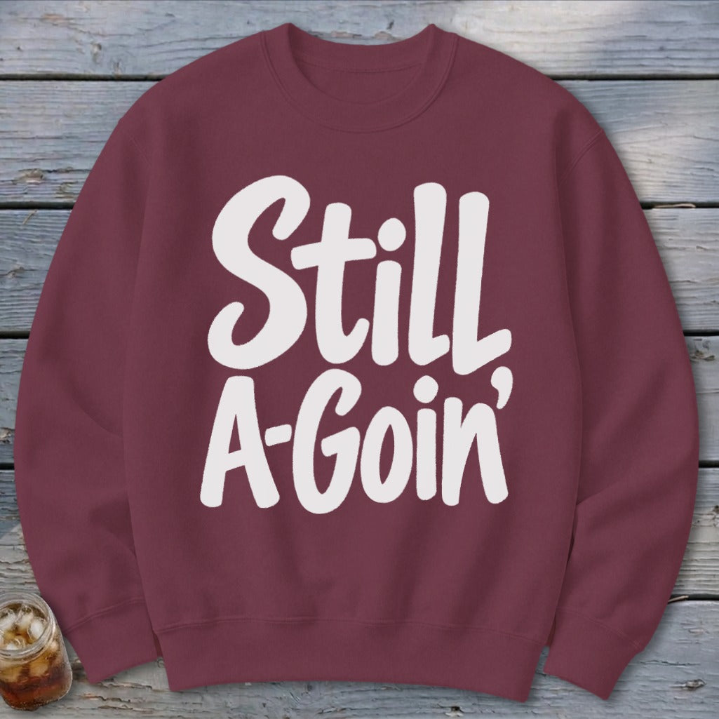 A maroon crewneck sweatshirt with the white text "Still A-Goin'" printed on the front.
