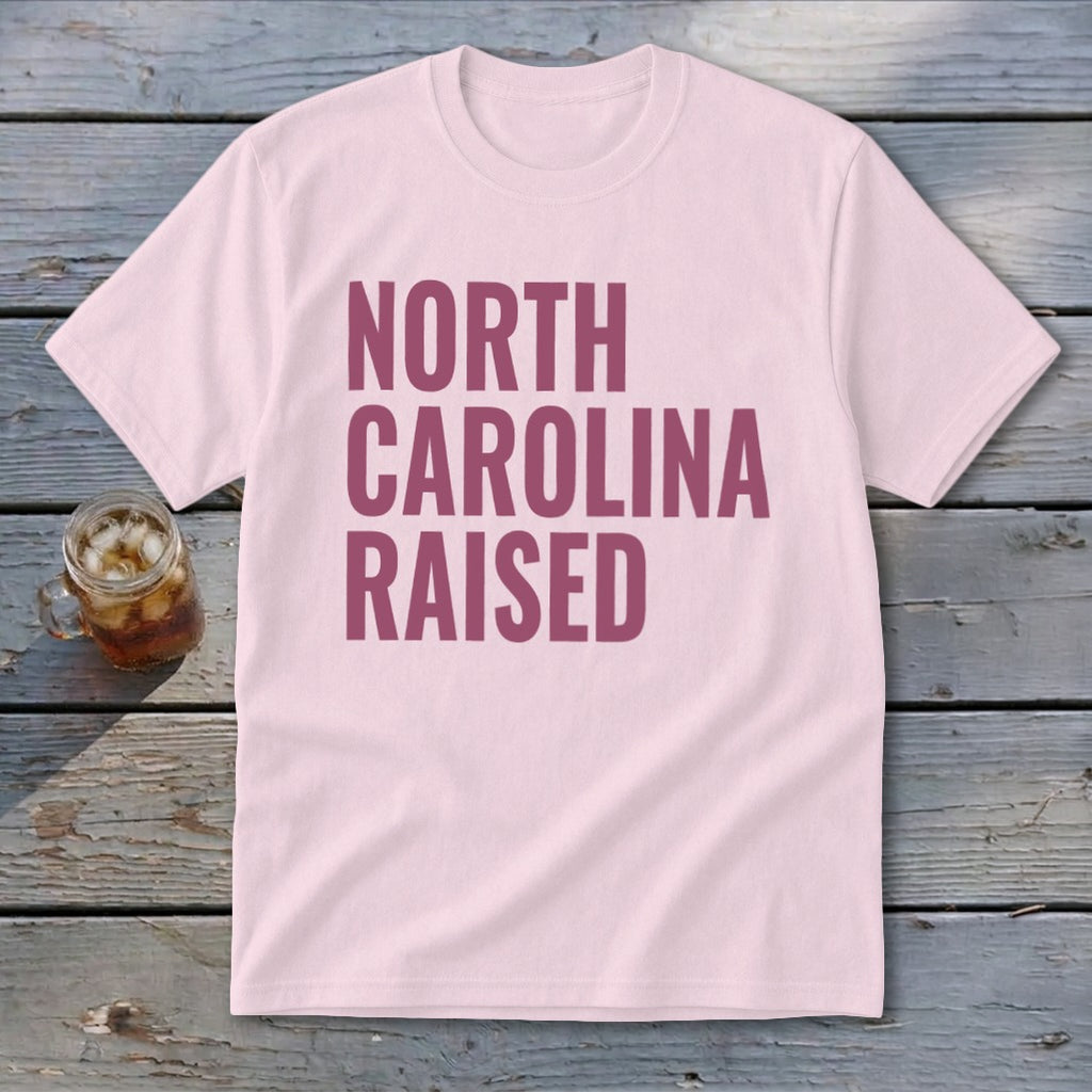 Pink t-shirt with "NORTH CAROLINA RAISED" text in burgundy.