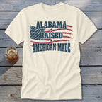 Cream t-shirt with distressed American flag and text "ALABAMA RAISED AMERICAN MADE".