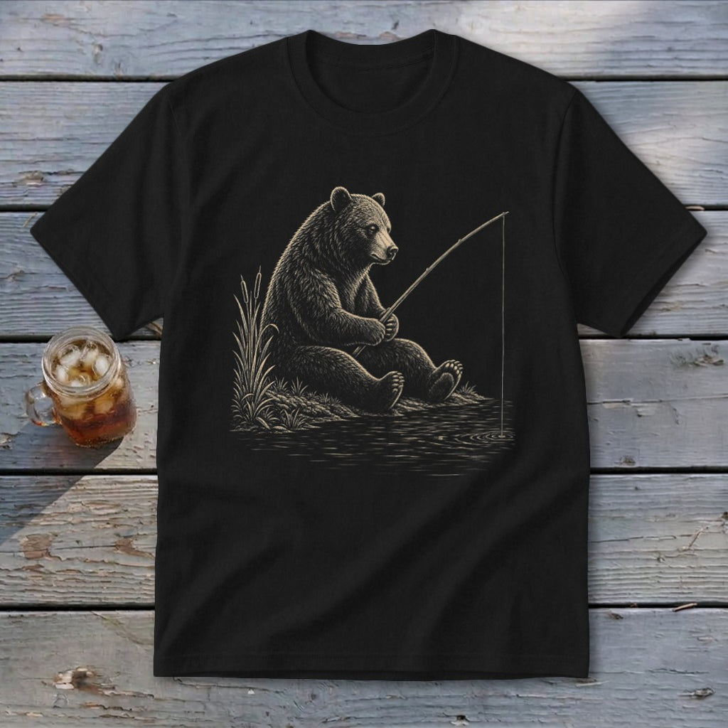 Black t-shirt featuring a bear fishing by a lake with reeds and a drink.