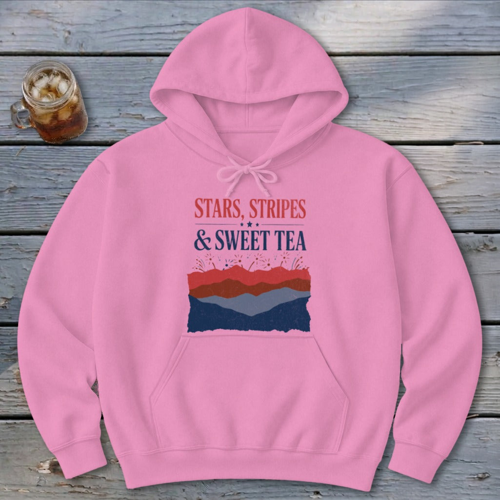 Pink hooded sweatshirt with front graphic text reading STARS, STRIPES & SWEET TEA over layered mountain silhouettes.