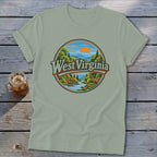 Light green t-shirt with a circular graphic featuring a mountain landscape, river, deer, and "West Virginia" text.