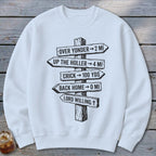 A white crewneck sweatshirt features a black graphic of a wooden signpost with directional distance text.