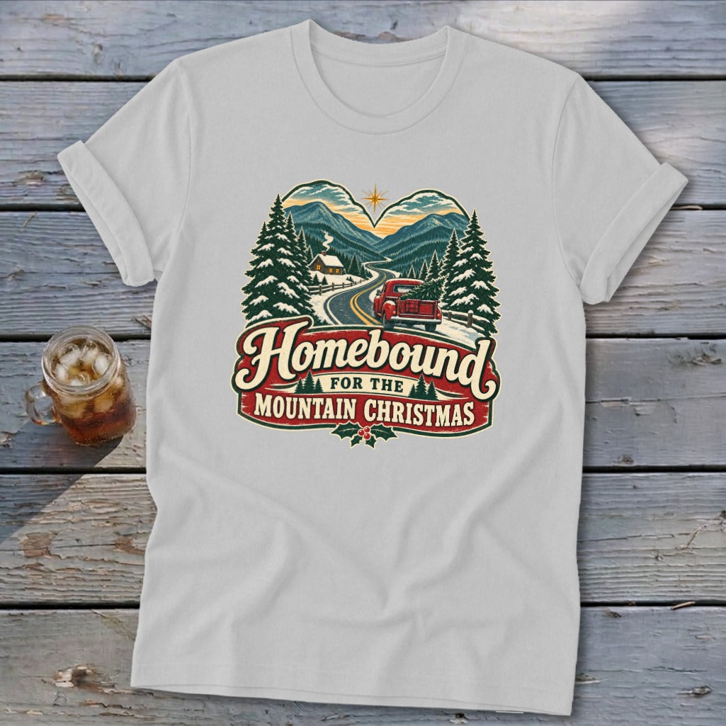 White t-shirt with "Homebound For The Mountain Christmas" text and vintage mountain scene graphic.