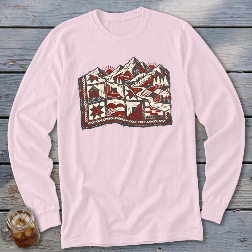 Light pink long-sleeve t-shirt featuring a detailed red and black landscape illustration of mountains and quilts.