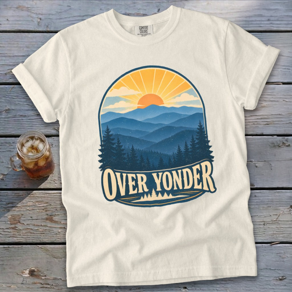 An off-white t-shirt featuring a retro mountain landscape graphic with a sunset and the text OVER YONDER.