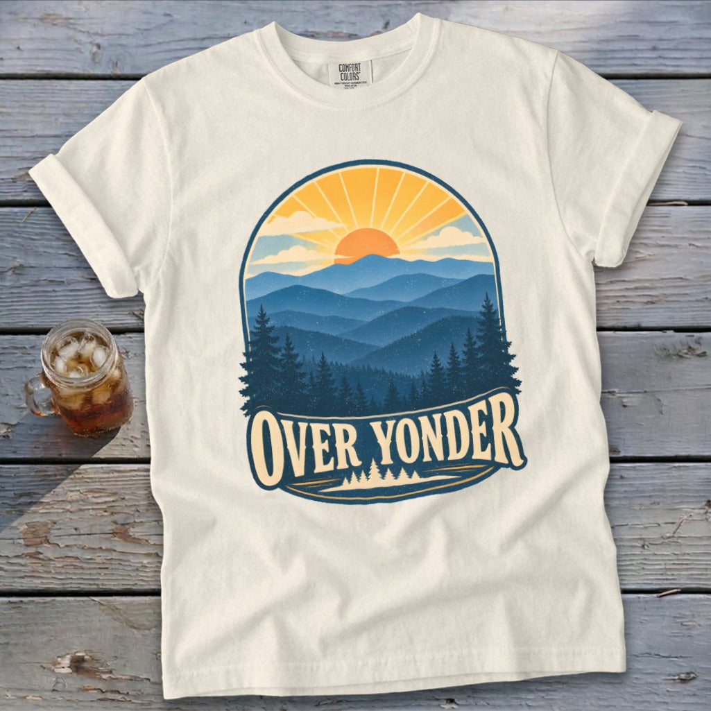 An off-white t-shirt featuring a retro mountain landscape graphic with a sunset and the text OVER YONDER.